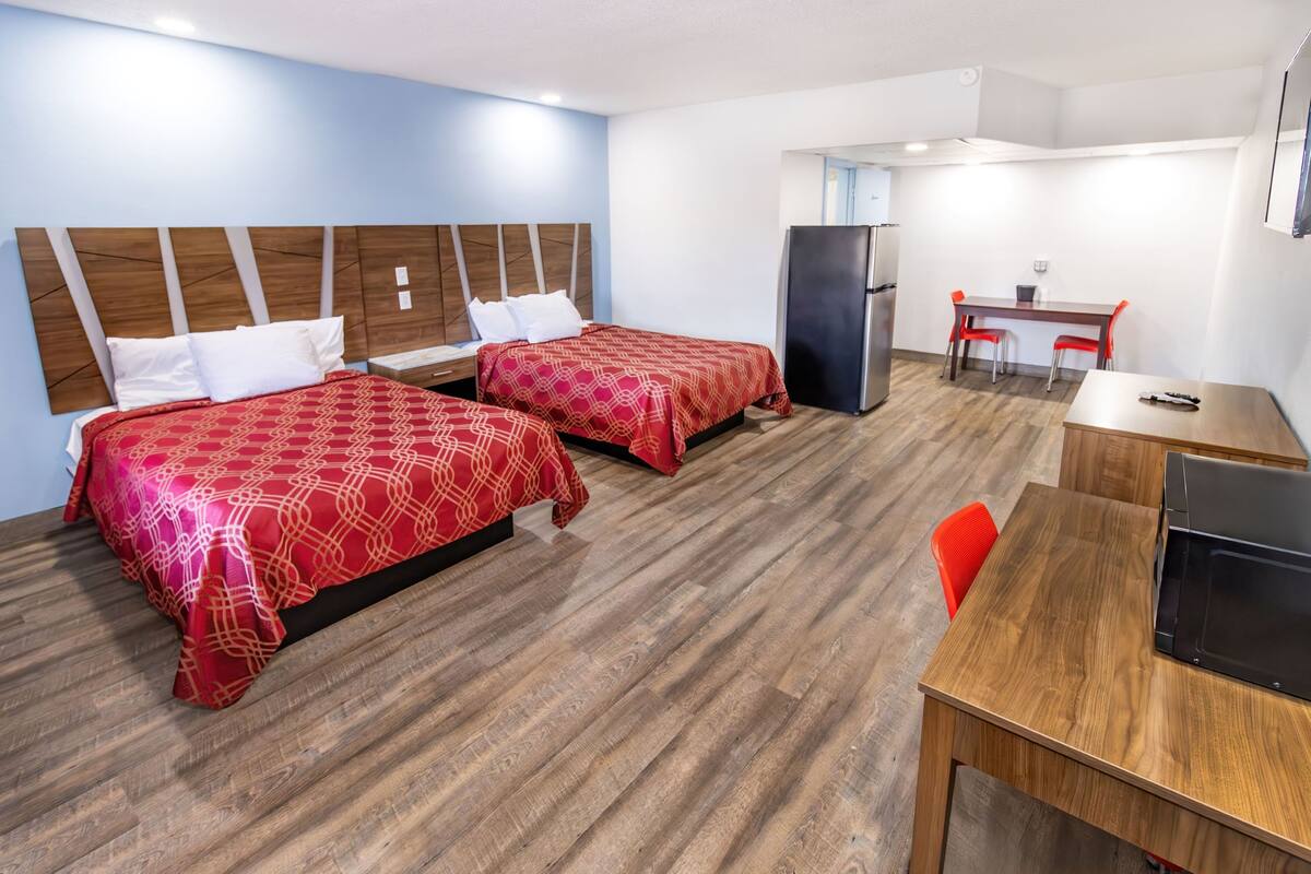 Habitación de hotel con dos camas, un escritorio, un refrigerador y un microondas.