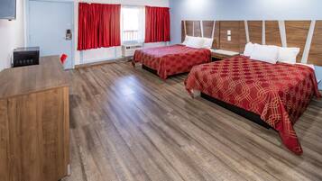 A hotel room with two beds, a desk, and a window with red curtains.