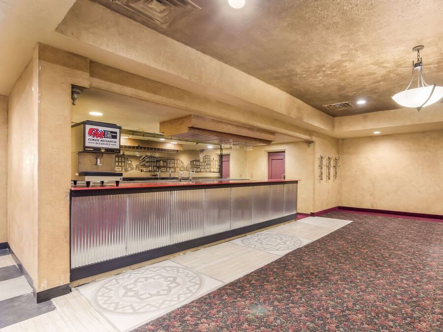A hotel lobby with a reception desk, a patterned carpet, and a large chandelier.