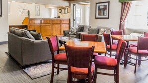 A hotel lobby with a reception desk, a sofa, a dining table with chairs, and a large window with curtains. - Quality Inn & Suites Golden - Denver West (Golden)