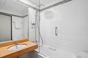 A modern bathroom with a glass-enclosed shower, a wooden vanity, and a white sink.