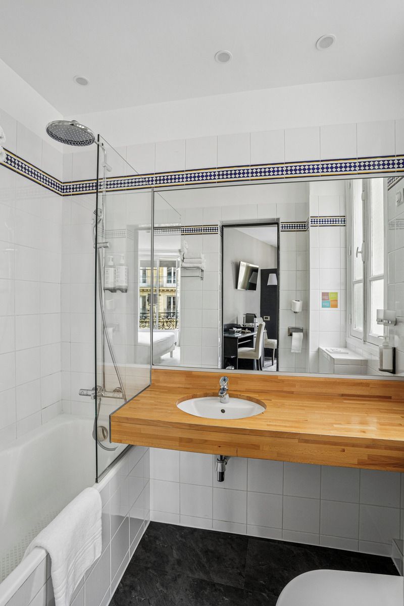 Een moderne badkamer met een douchecabine van glas, een houten wastafelmeubel en een grote spiegel.