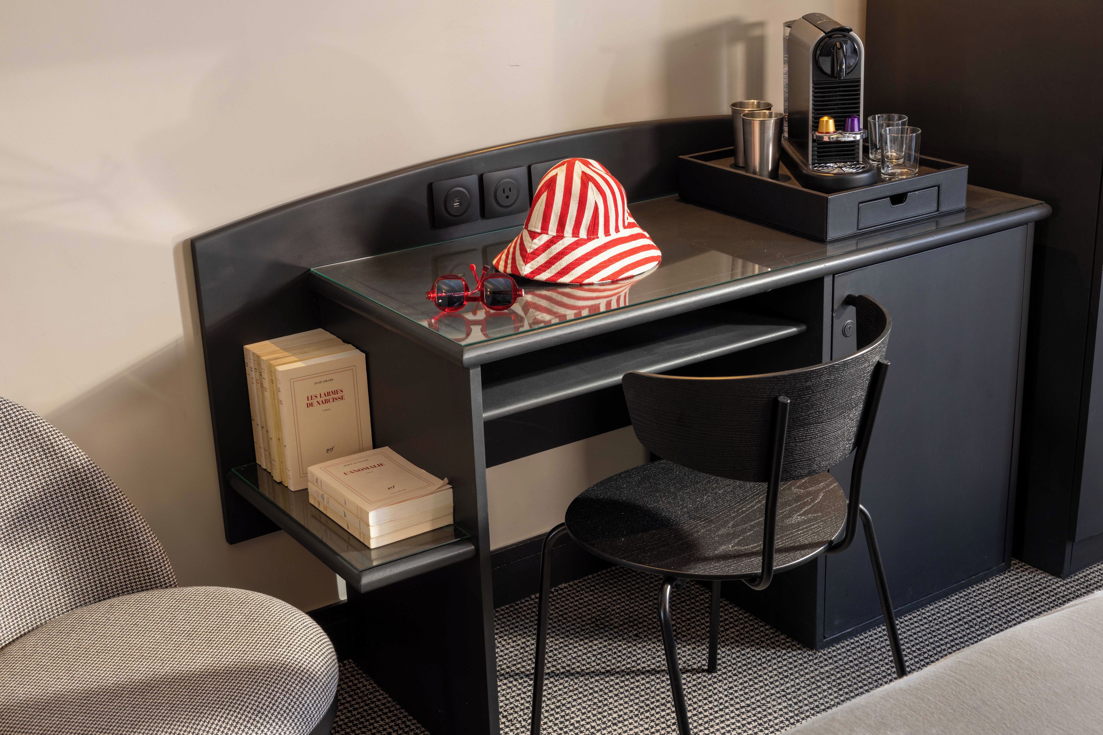 Habitació d'hotel amb escriptori, cadira, màquina de cafè i nevera minibar.