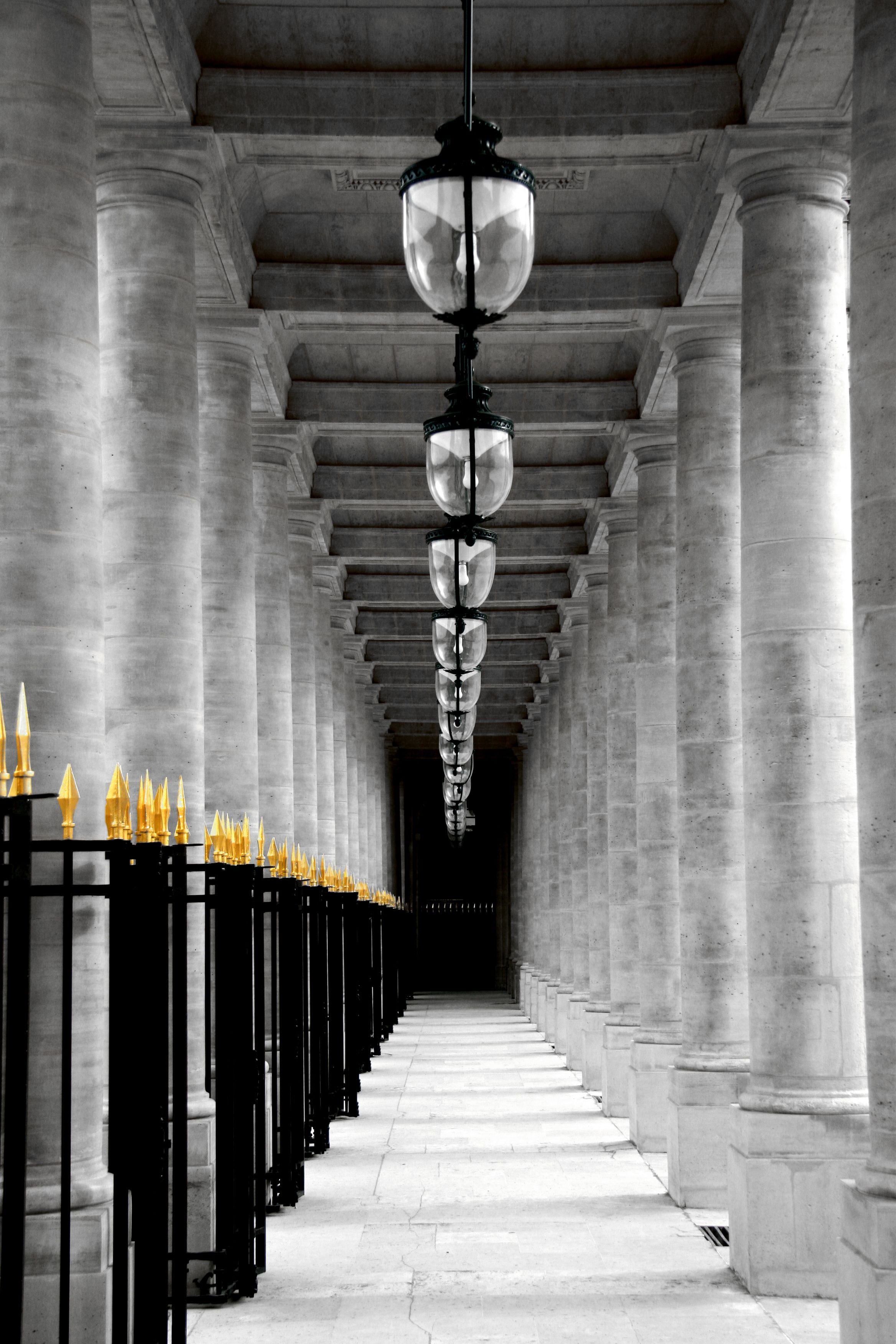 A corridor with columns and a series of black lantern-style lights.