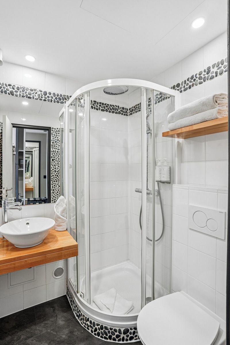 A modern bathroom with a glass-enclosed shower, a white sink, and a toilet.