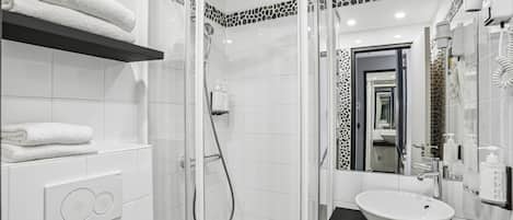 A modern bathroom with a glass-enclosed shower, a white sink, and a towel rack.