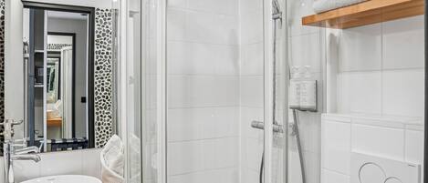 A modern bathroom with a glass-enclosed shower, a white sink, and a toilet.