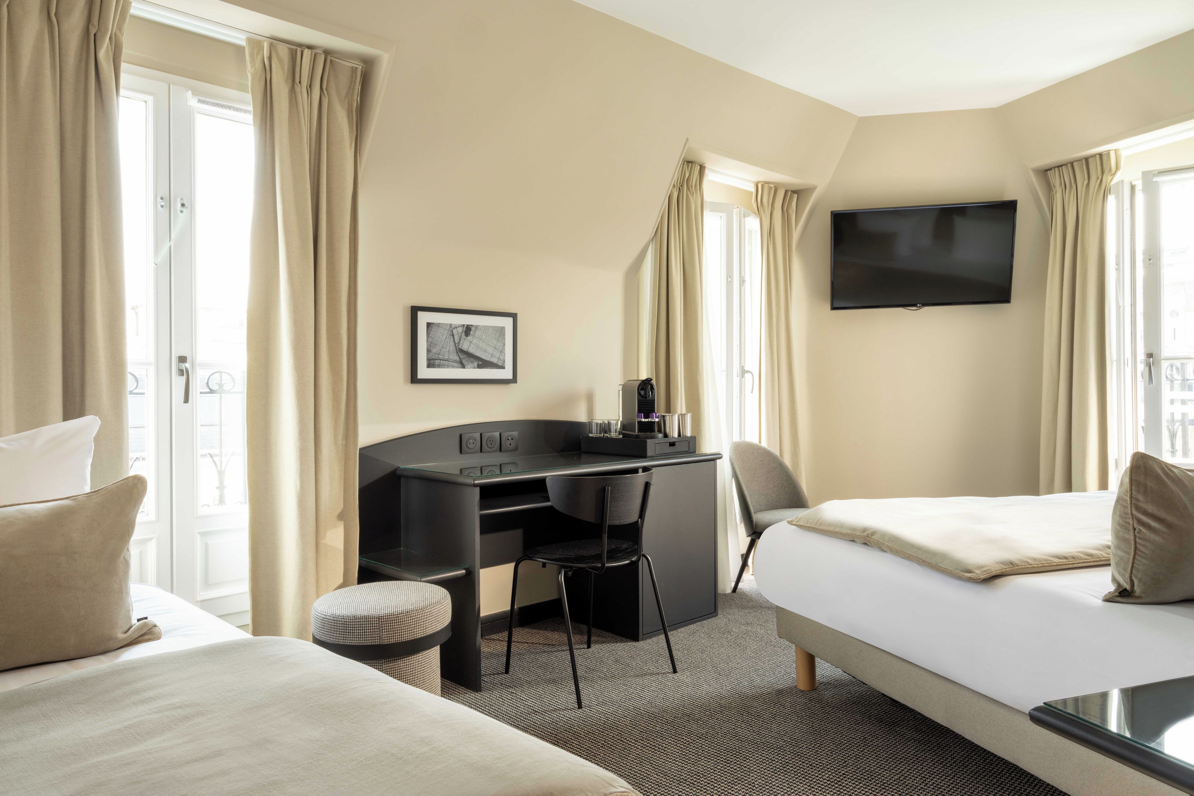 A hotel room with a bed, a desk, a chair, a television, and a window with curtains.