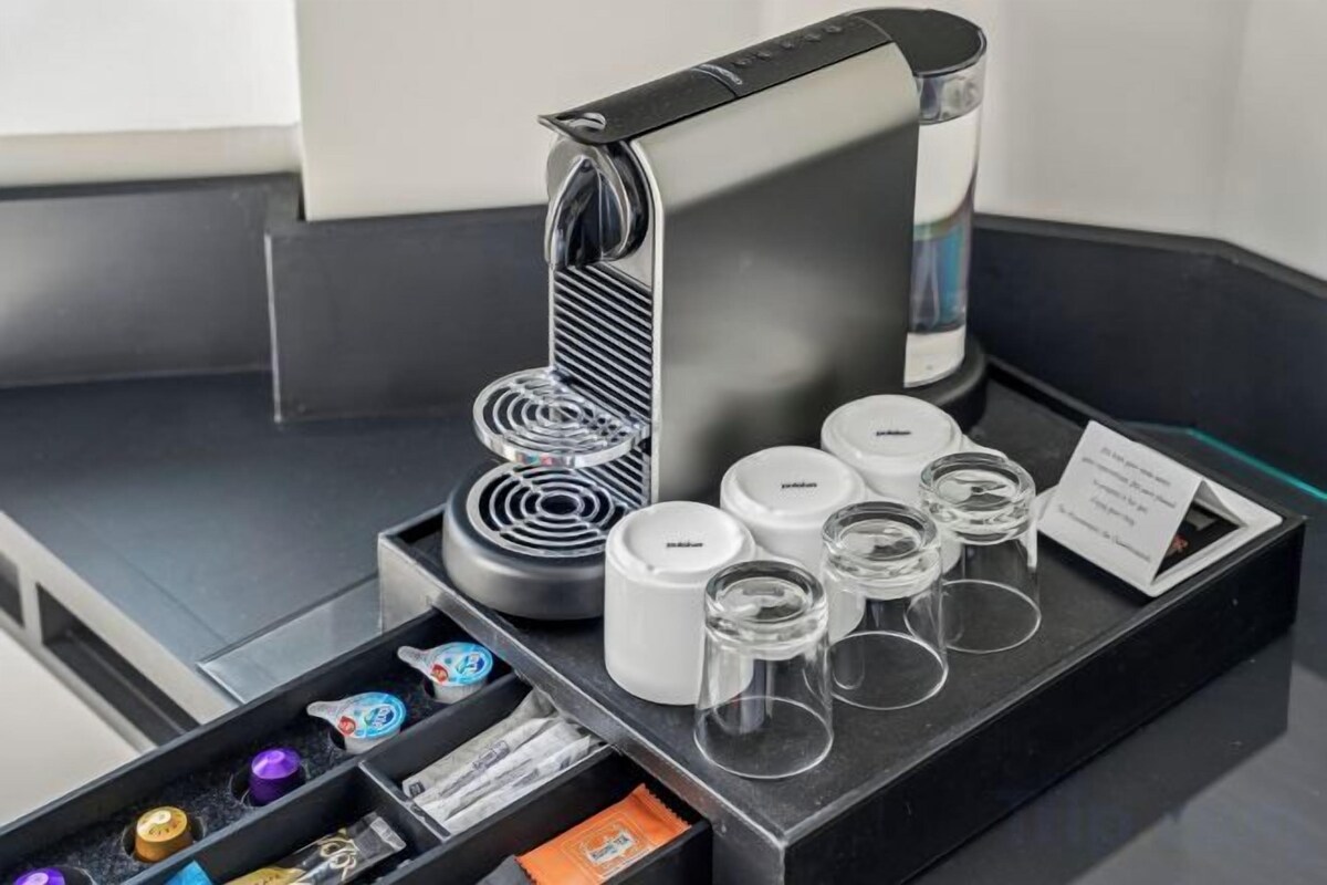 A coffee station with a coffee machine, cups, and a tray with coffee pods and a menu.
