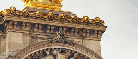 A grand entrance with a statue of a woman holding a torch, columns, and intricate carvings.