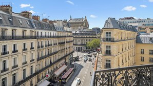 A view of a street lined with historic buildings, including a prominent building with a statue on top. - Hôtel Excelsior Opéra (Paris)