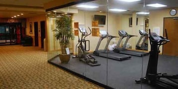 Un gimnasio con cintas de correr, bicicletas estáticas y un espejo grande.
