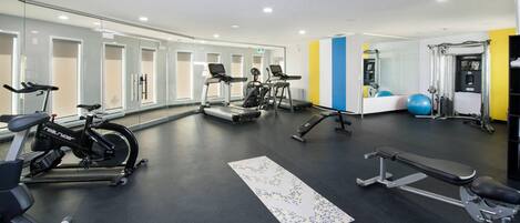 A gym with exercise equipment, a bench, and a mirrored wall.