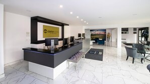 A hotel reception area with a marble floor, a reception desk, seating area, and a large window with a view. - Clarion Pointe Medicine Hat Saamis Tepee (Medicine Hat)