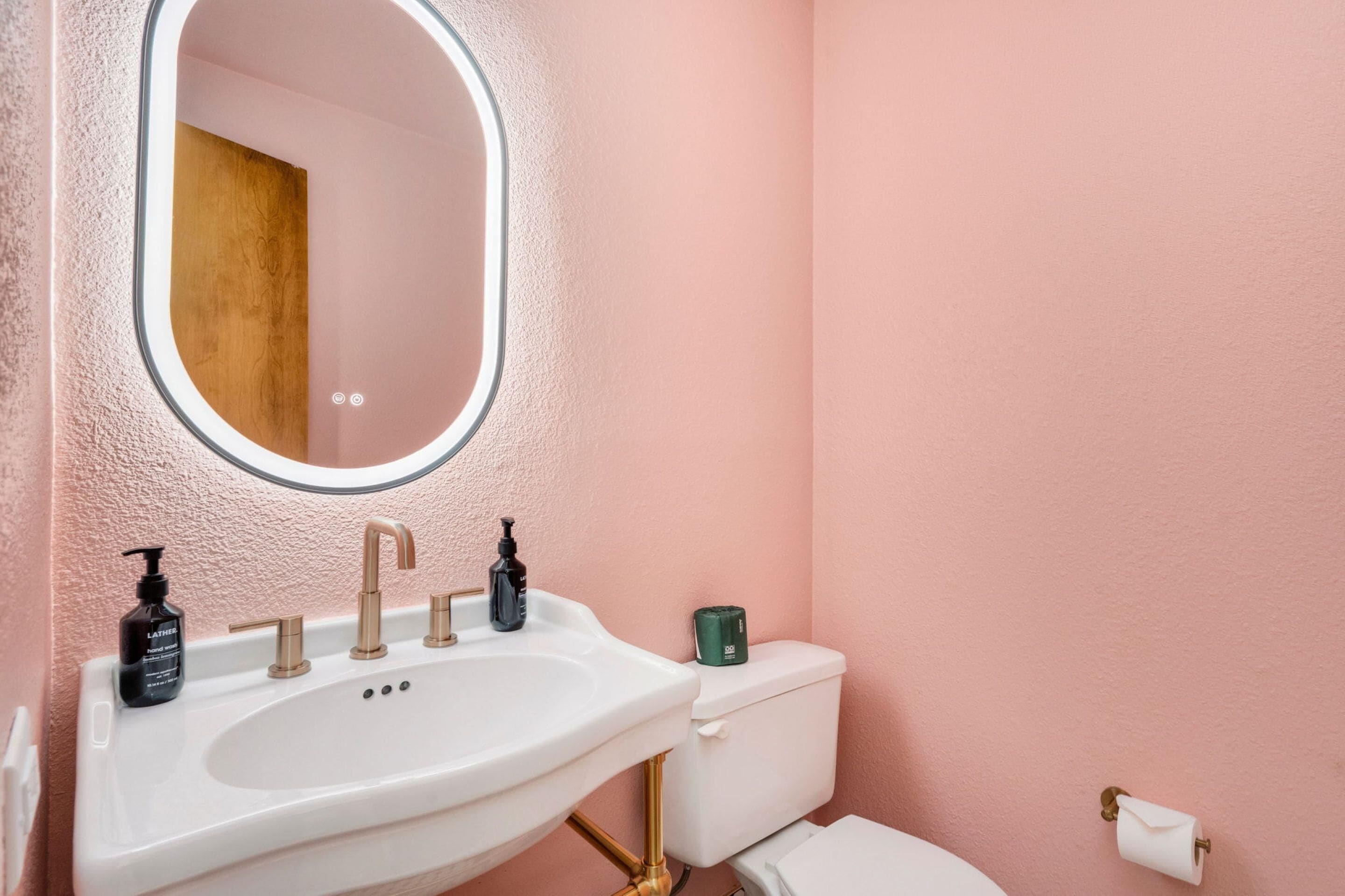 A bathroom with a white sink, a mirror, and a toilet.