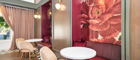 A modern interior with seating and tables, a large floral mural, and a view through a window.