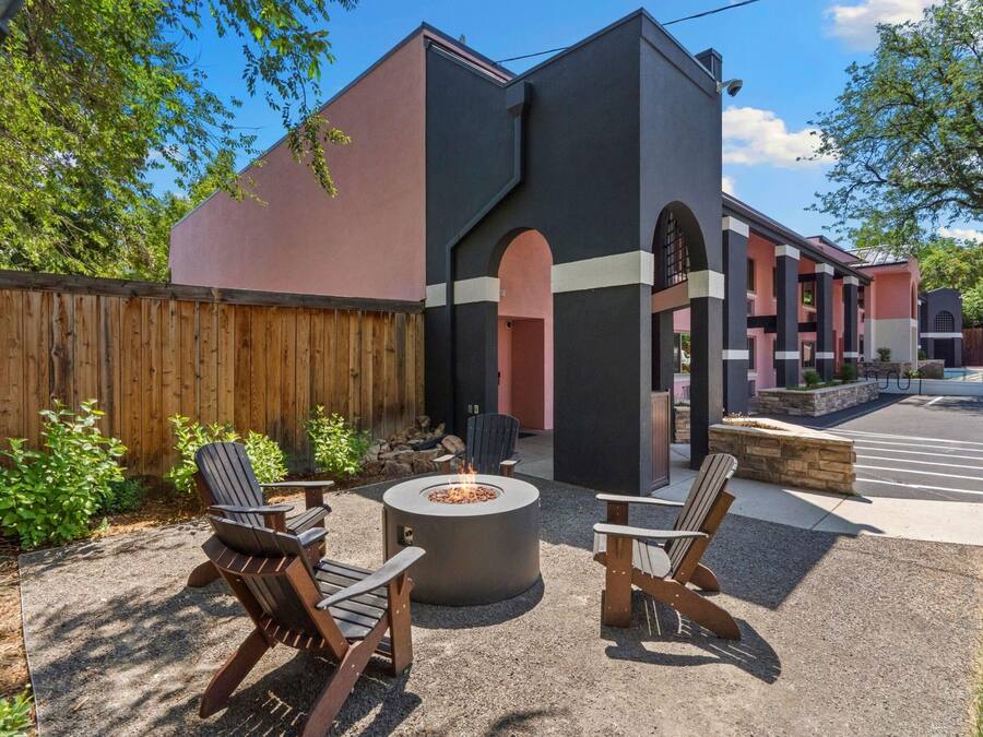 A patio area with Adirondack chairs, a fire pit, and a wooden fence.