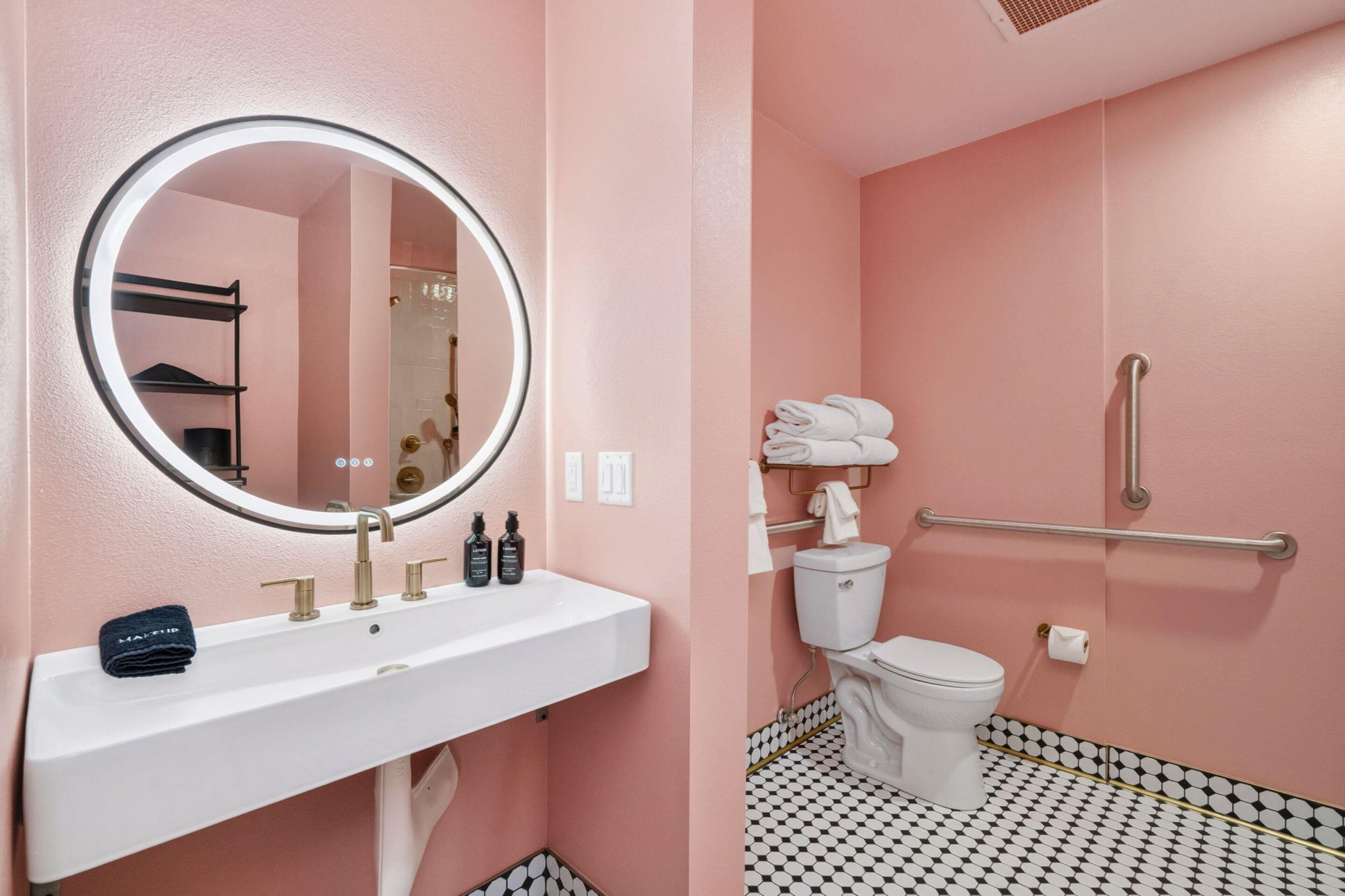 Ein Badezimmer mit einem weißen Waschbecken, einem runden Spiegel, einer Toilette und einer Duschkabine.