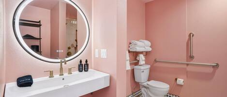 Ein Badezimmer mit einem weißen Waschbecken, einem runden Spiegel, einer Toilette und einer Duschkabine.