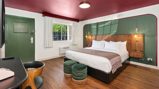 A bedroom with a bed, bedside table, lamp, and a green door.