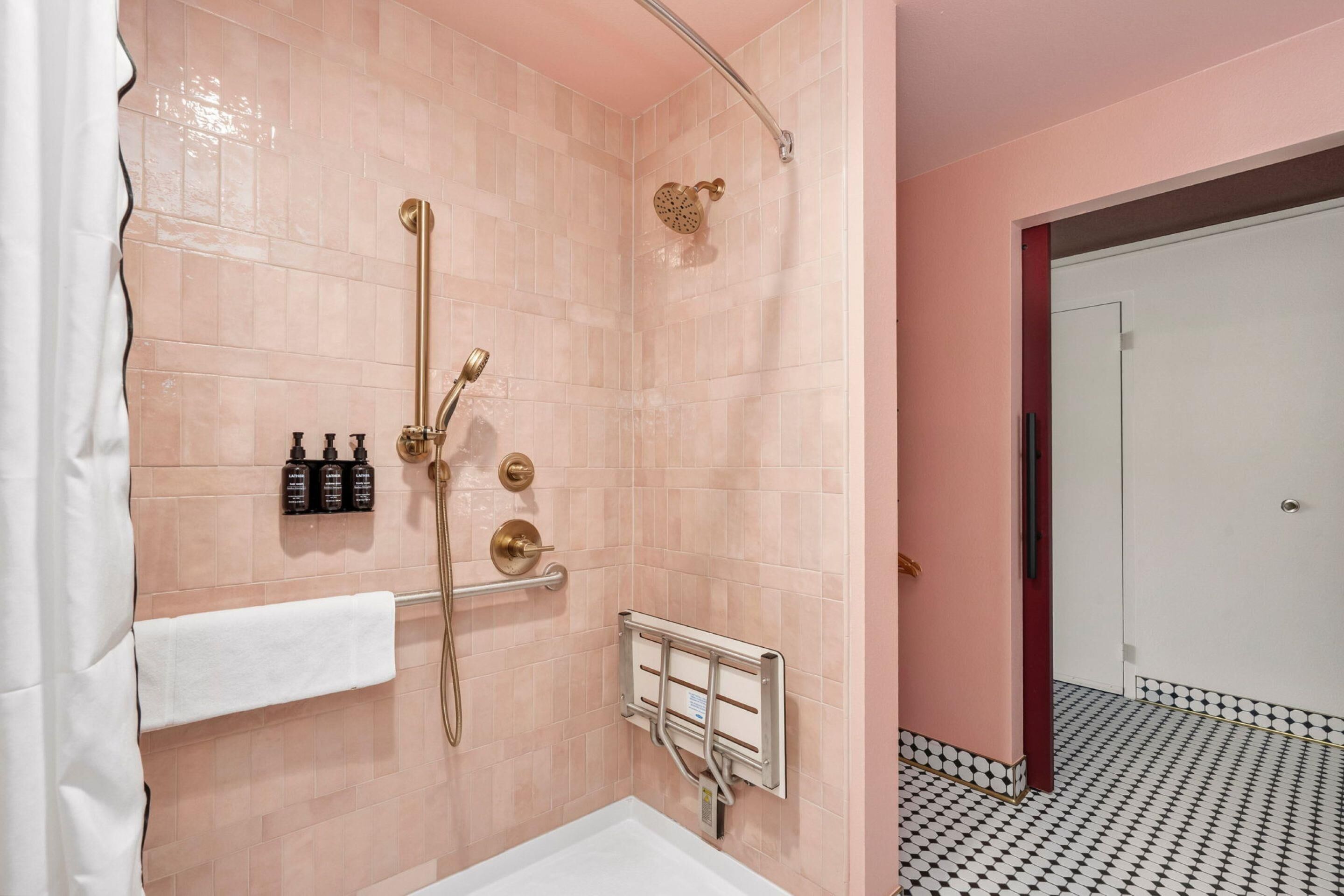 A bathroom with a shower, a towel rack, and a hand dryer.