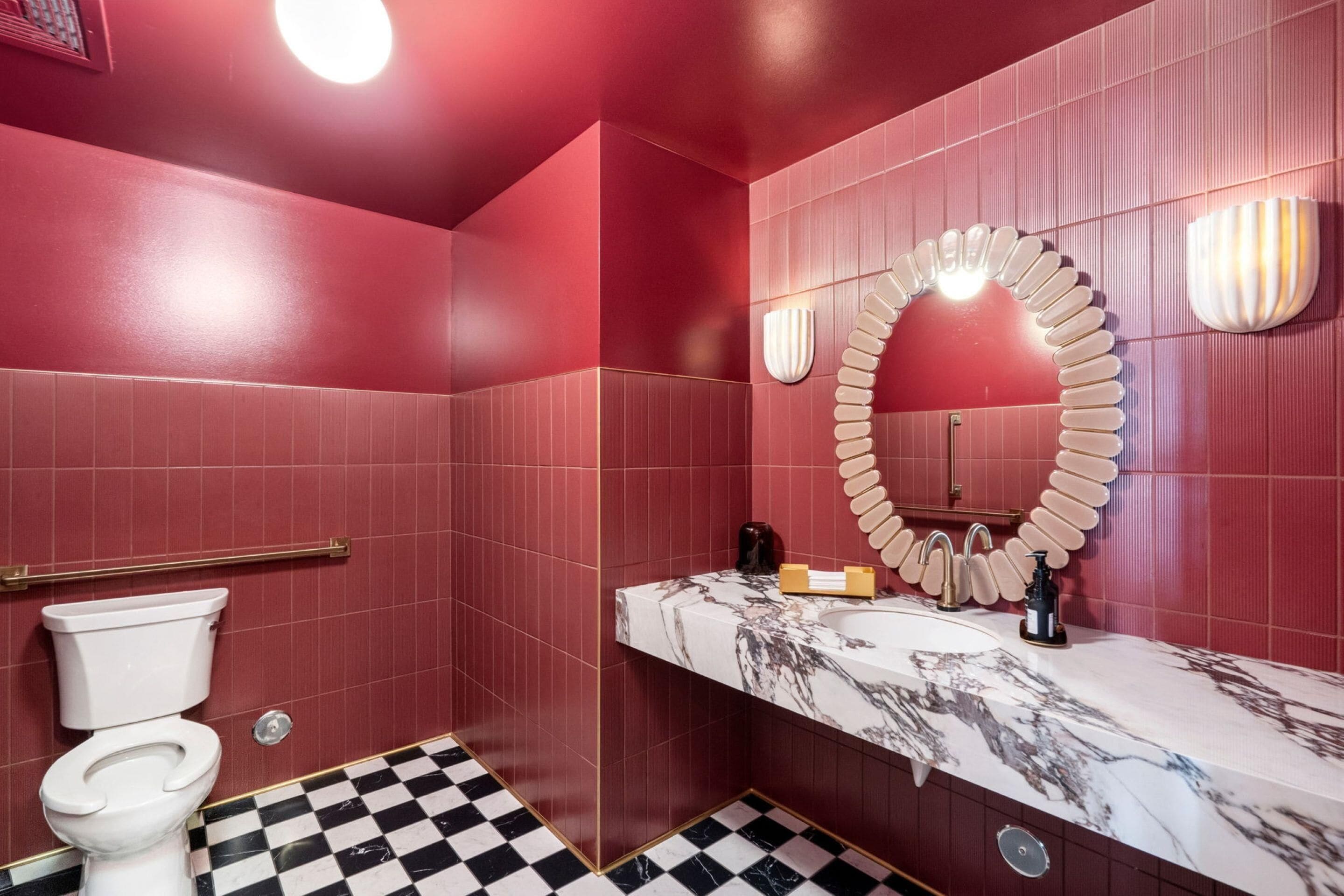 A bathroom with a white toilet, a marble sink, and a mirror with a unique design.