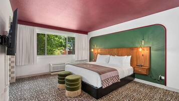 A hotel room with a bed, a TV, a window with curtains, a heater, and a leopard print floor.