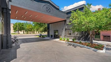 A modern building with a covered entrance, a checkered wall, and a bike parking area.