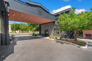 A modern building with a covered entrance, a checkered wall, and a bike parking area. - The Buxton, BW Signature Collection by Best Western (Fort Collins)
