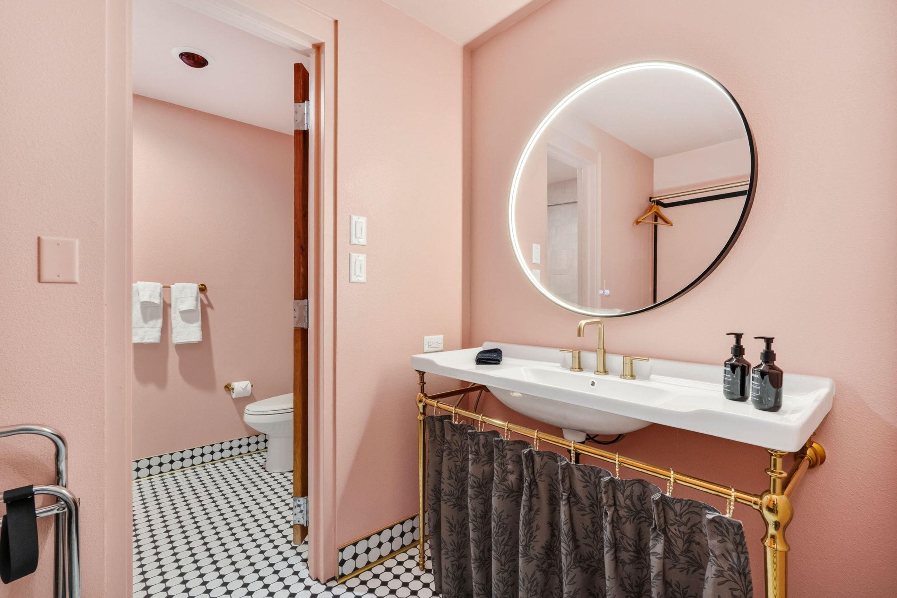 A bathroom with a white sink, a round mirror, and a shower curtain.
