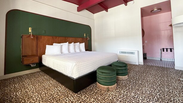 A bedroom with a bed, a headboard, a wardrobe, a bedside table, a radiator, and a leopard print carpet.