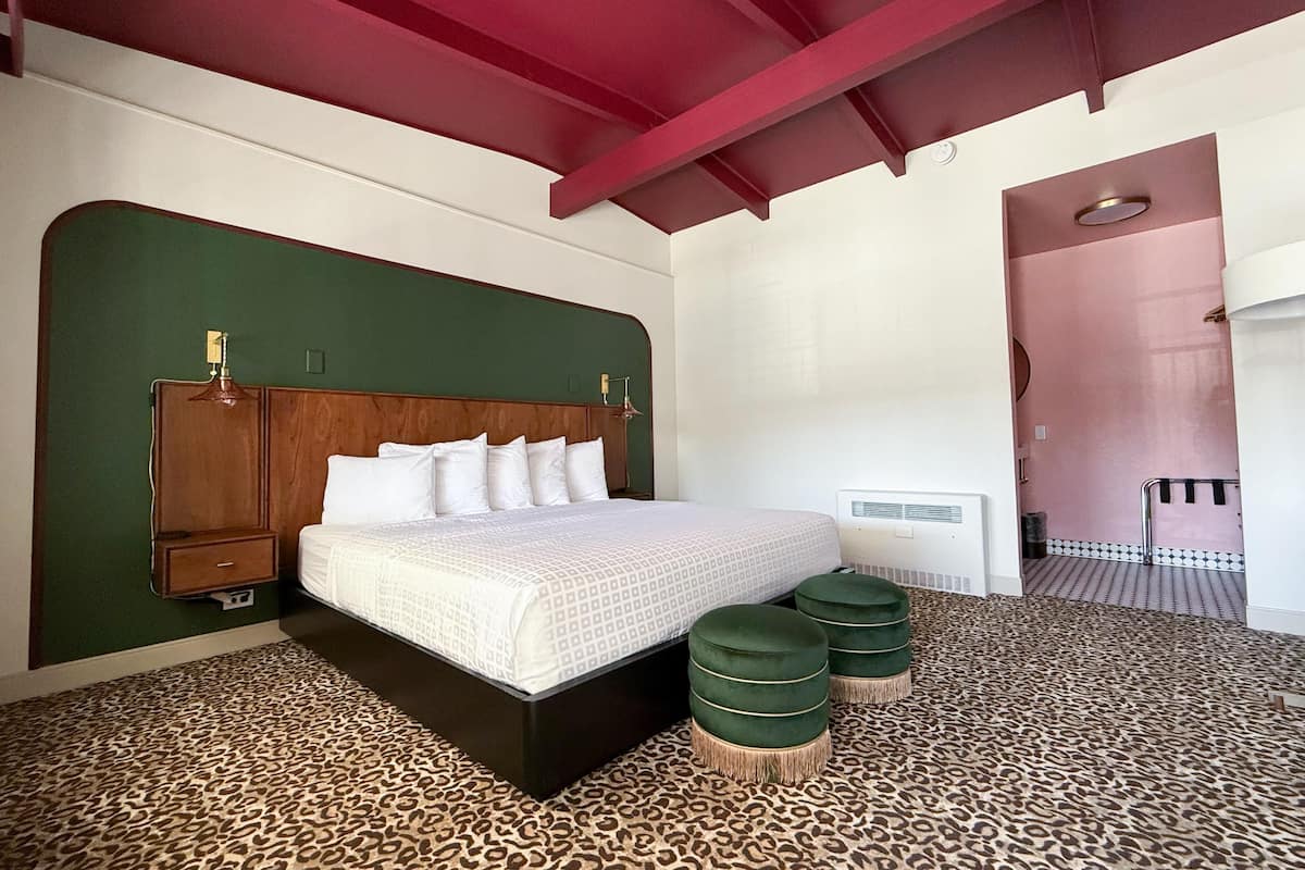 Une chambre à coucher comprenant un lit, une tête de lit, une armoire, une table de chevet, un radiateur et un tapis à motifs léopard.