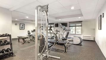 Un gimnasio moderno con varios equipos de ejercicio, incluyendo cintas de correr y máquinas de pesas.