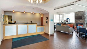 Un hall de hotel con mostrador de recepción, zona de estar y chimenea.