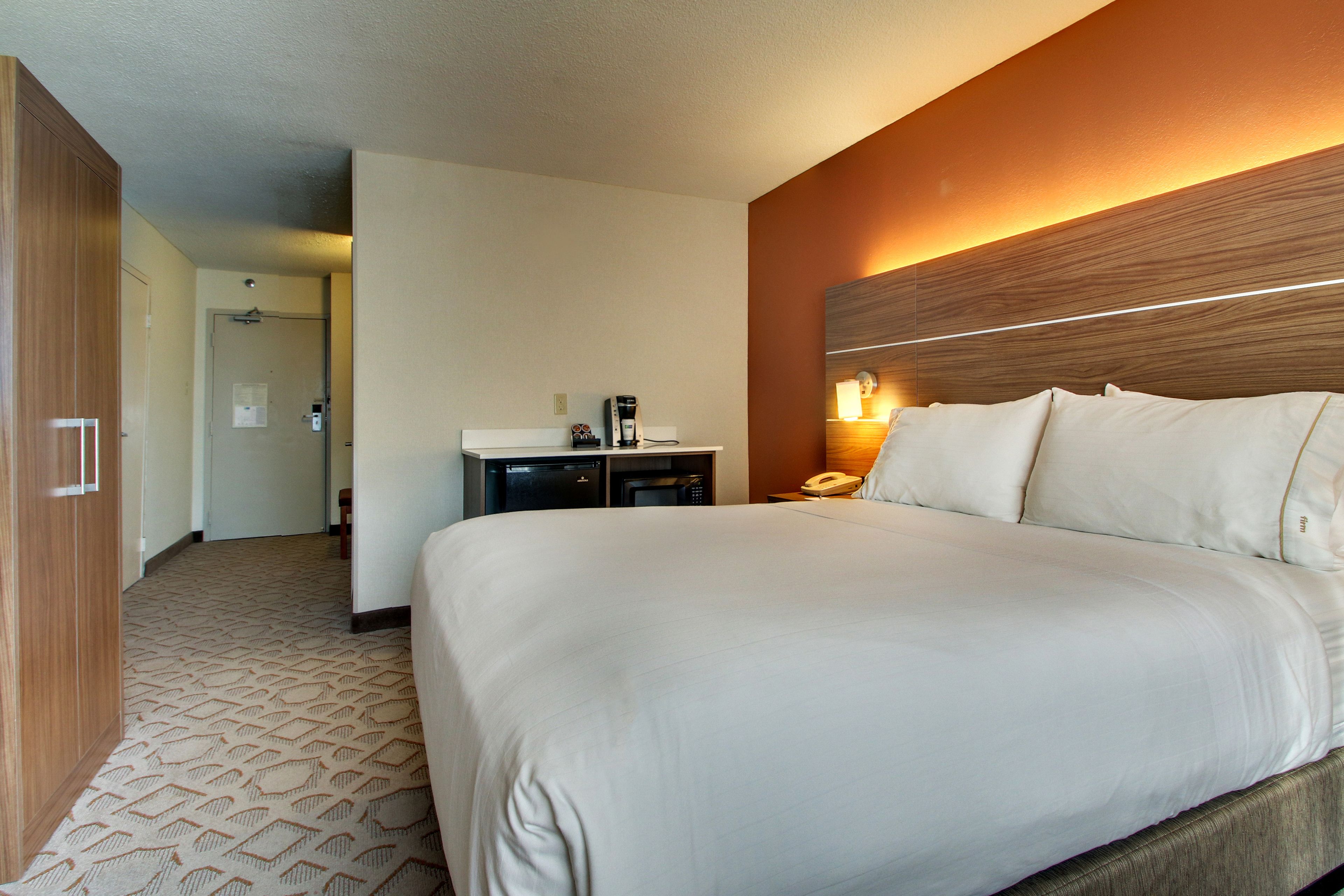 Habitación de hotel con una cama grande, un escritorio con lámpara y un cabecero de madera.