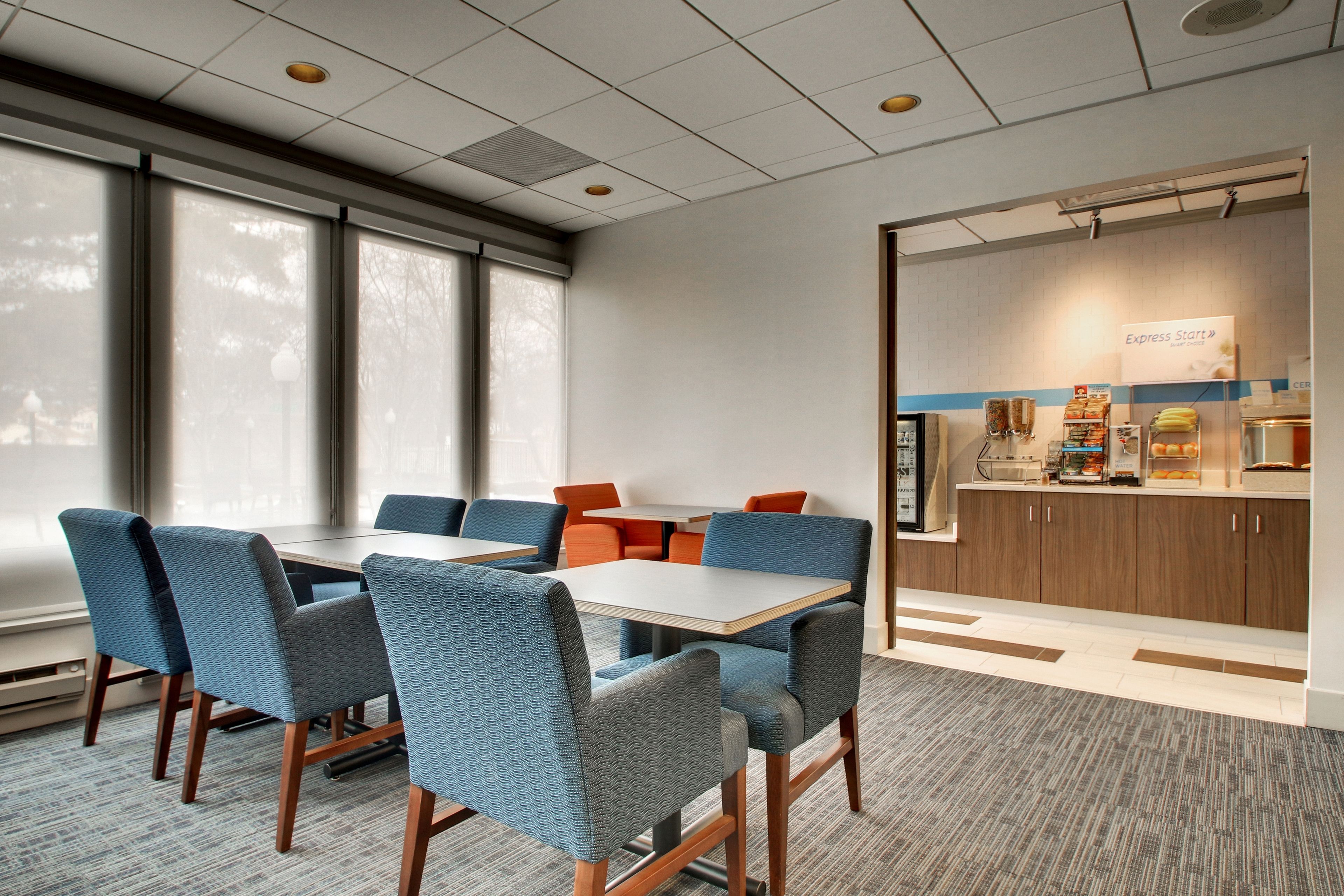 A conference room with a large table, blue chairs, and a kitchenette area with a sign reading "Express Start".
