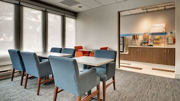 A conference room with a large table, blue chairs, and a kitchenette area with a sign reading "Express Start".