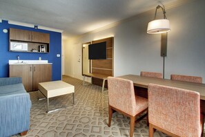 Ein modernes Hotelzimmer mit Essbereich, einem Wand-Fernseher und einer Mikrowelle auf der Arbeitsfläche.
