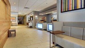 A lobby with a wooden bench, a reception desk, and a colorful artwork on the wall. - Holiday Inn Express Poughkeepsie by IHG (Poughkeepsie)