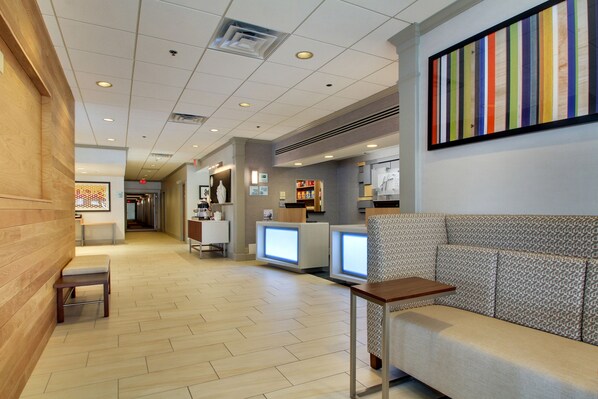 A lobby with a wooden bench, a reception desk, and a colorful artwork on the wall. - Holiday Inn Express Poughkeepsie by IHG (Poughkeepsie)