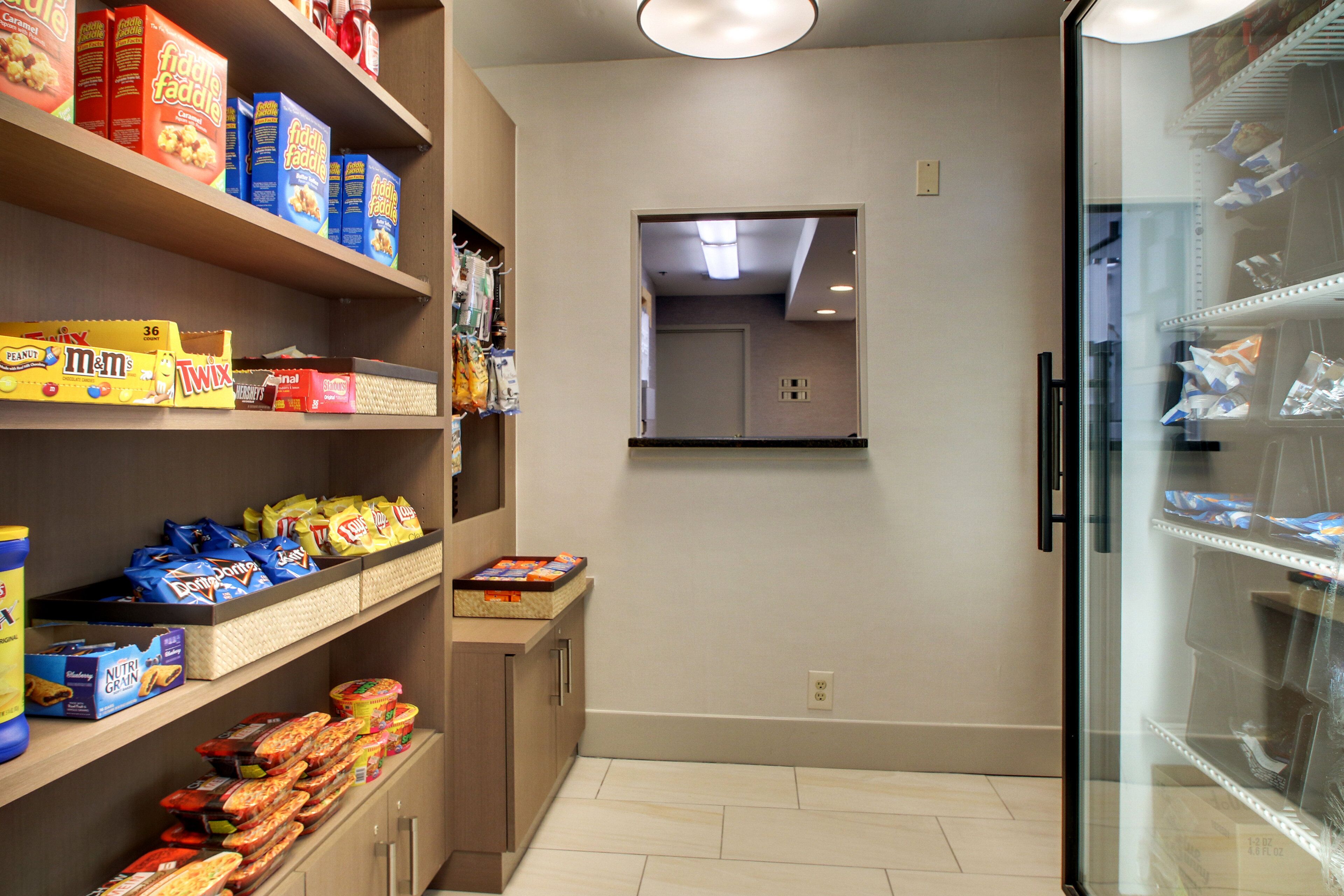 A kitchen with shelves stocked with snacks and a refrigerator.
