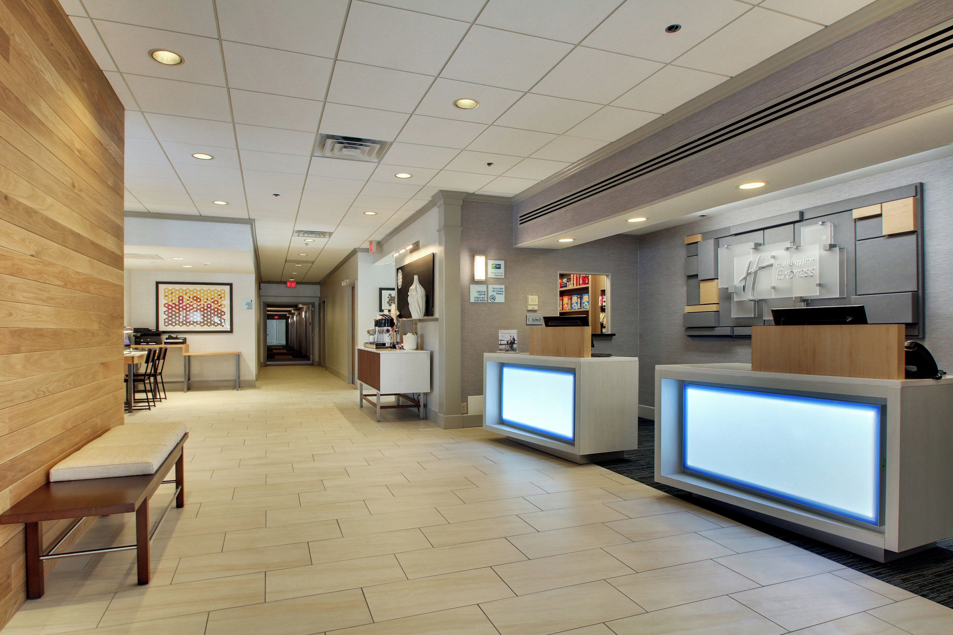 A hotel reception area with a wooden wall, a reception desk, a seating area, and a hallway leading to other rooms.