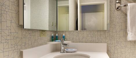 A modern bathroom with a large mirror, a sink, and a towel rack.