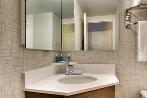 A modern bathroom with a large mirror, a sink, and a towel rack.