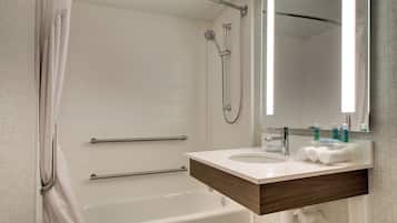 A modern bathroom with a bathtub, a shower, and a vanity with a sink and mirror.