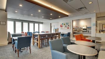 A modern interior with a large meeting table, comfortable seating, and a kitchen area.