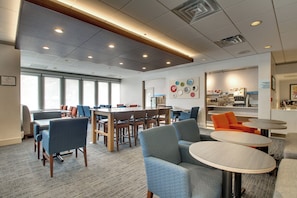 A modern interior with a large meeting table, comfortable seating, and a kitchen area.