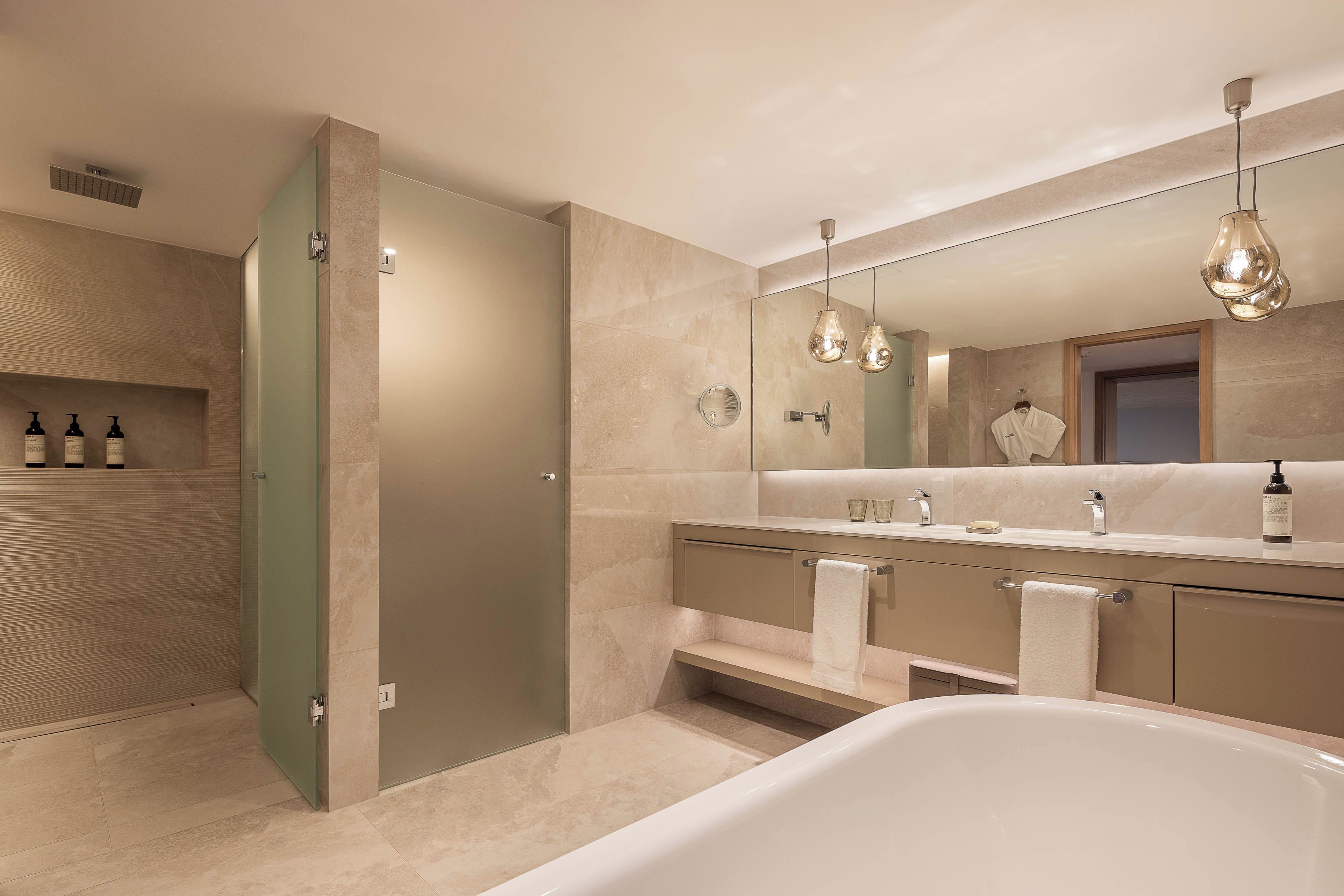 Un baño moderno con una bañera independiente, un espejo grande y un tocador con perchero.