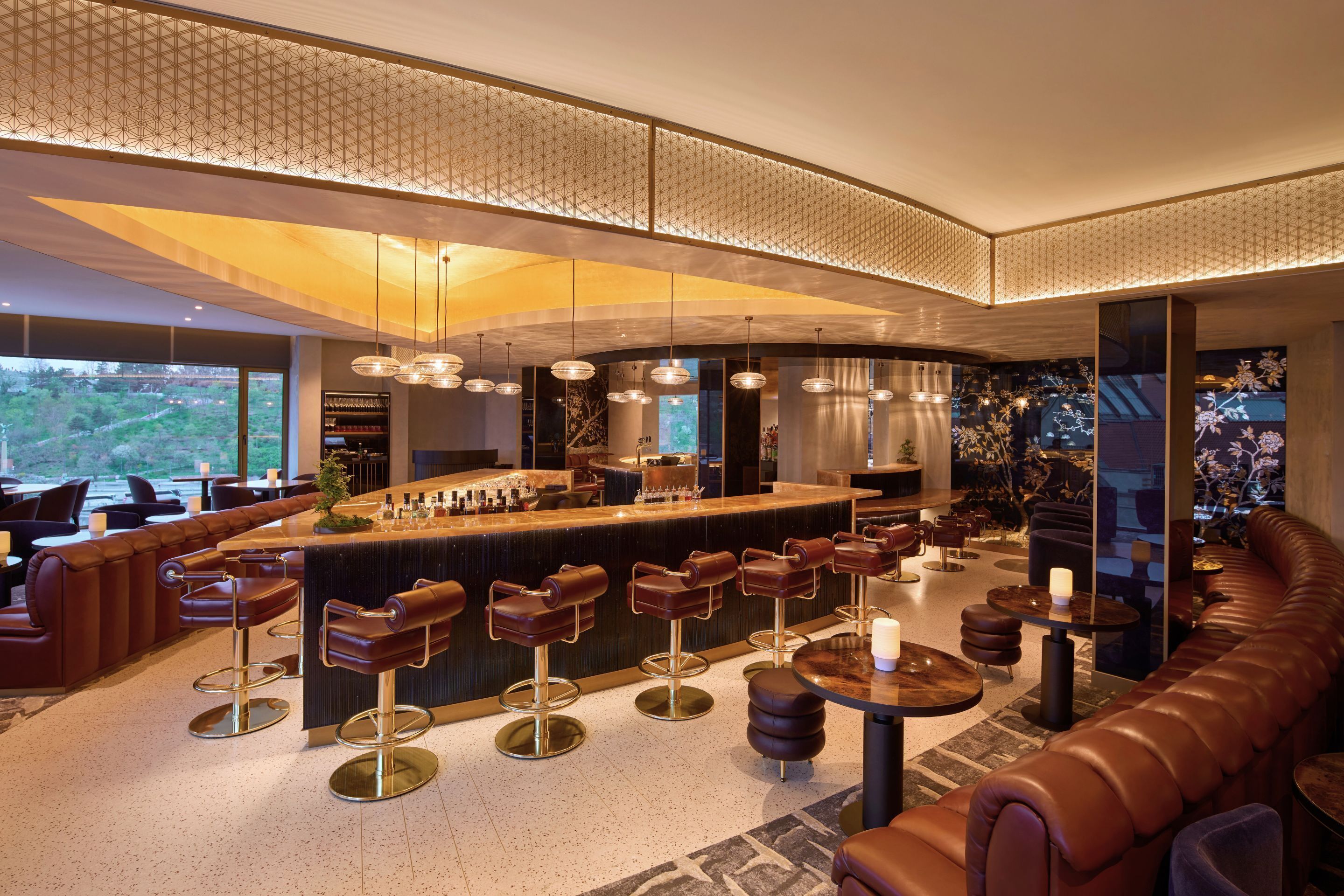 Uma área de bar moderna com assentos de couro, balcão central e iluminação pendente.