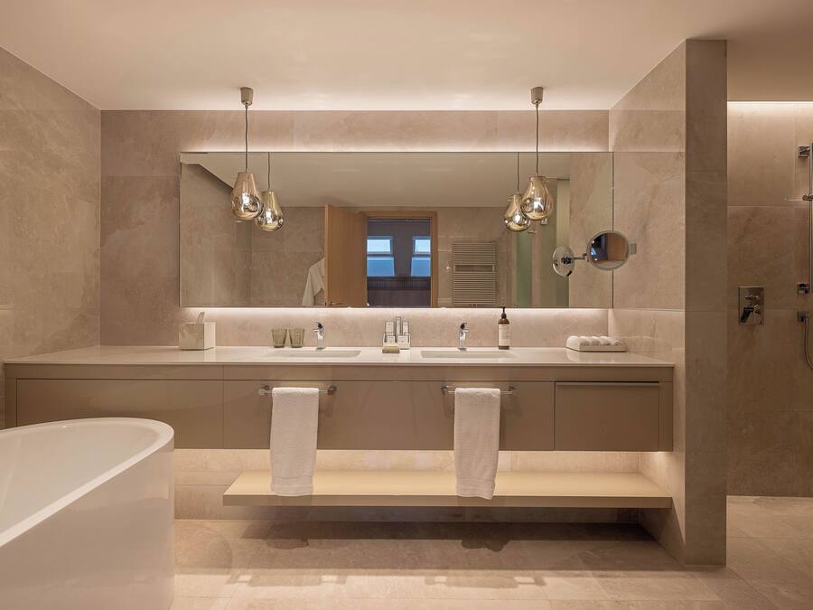 A modern bathroom with a bathtub, two sinks, a vanity, and a walk-in shower.